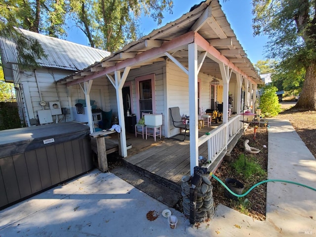 wooden deck with a hot tub and covered porch