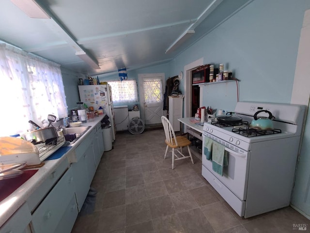 kitchen featuring sink, vaulted ceiling, white appliances, and washer / dryer