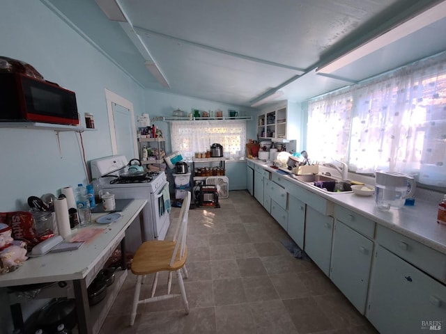 kitchen with vaulted ceiling, white range with gas stovetop, and sink