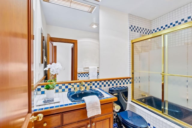 full bathroom featuring toilet, vanity, tile walls, backsplash, and combined bath / shower with glass door