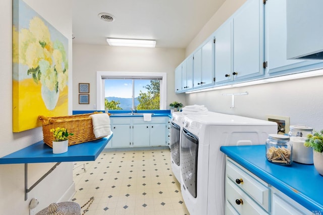 laundry area with washing machine and clothes dryer, cabinets, sink, and light tile floors