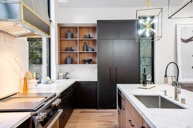 kitchen with electric stove, sink, light wood-type flooring, light stone counters, and pendant lighting