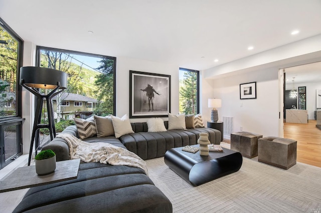 living room featuring an inviting chandelier, light hardwood / wood-style floors, a fireplace, and a wall of windows