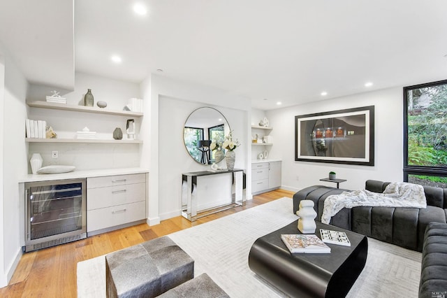 living room featuring bar area, light wood-type flooring, and wine cooler