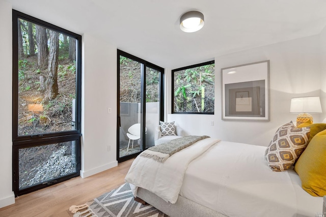 bedroom with multiple windows, light hardwood / wood-style floors, and access to exterior