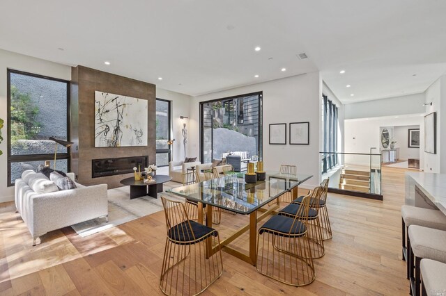 dining space with light wood-type flooring, a wealth of natural light, and a fireplace