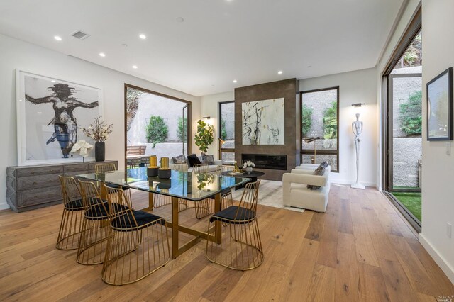 dining area with a large fireplace and light hardwood / wood-style floors