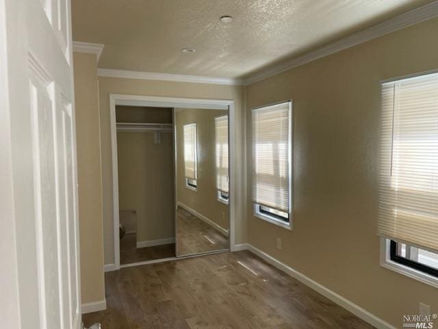 unfurnished bedroom featuring crown molding, a closet, and dark wood-type flooring