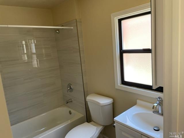 full bathroom featuring tiled shower / bath, toilet, and vanity