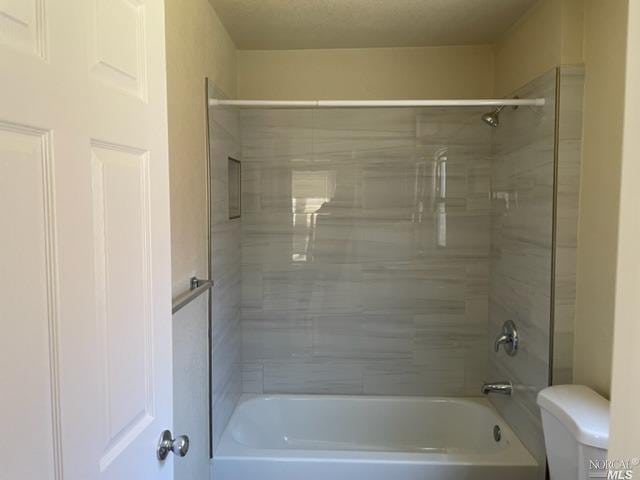 bathroom with tiled shower / bath combo and toilet