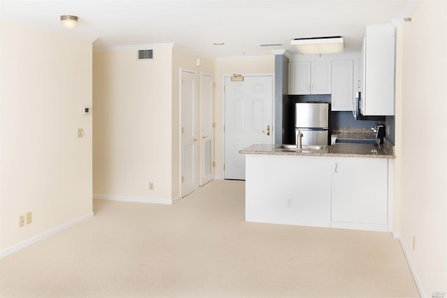 kitchen featuring light colored carpet, stove, kitchen peninsula, white cabinets, and stainless steel refrigerator