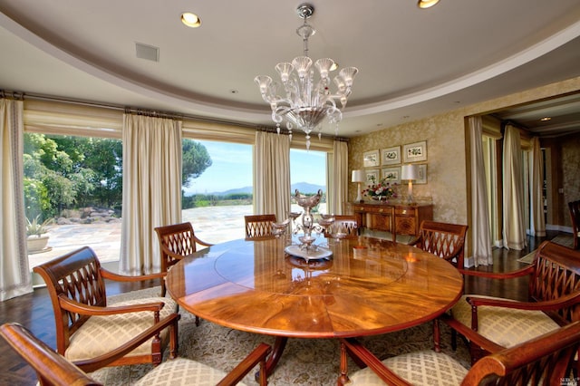 dining space with a notable chandelier, a raised ceiling, and hardwood / wood-style floors