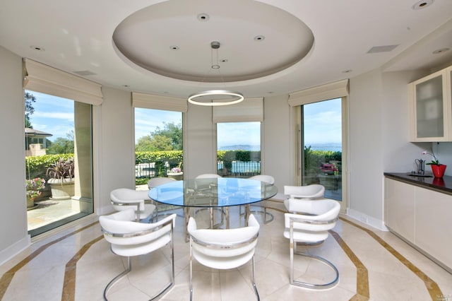 dining area with light tile floors and a tray ceiling