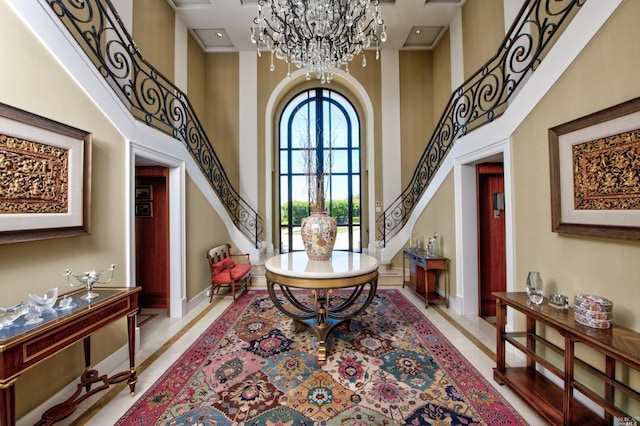 foyer with a notable chandelier, crown molding, light tile floors, and a towering ceiling