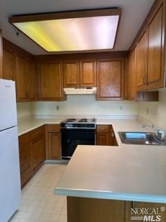 kitchen with light tile floors, range with electric stovetop, white fridge, and sink