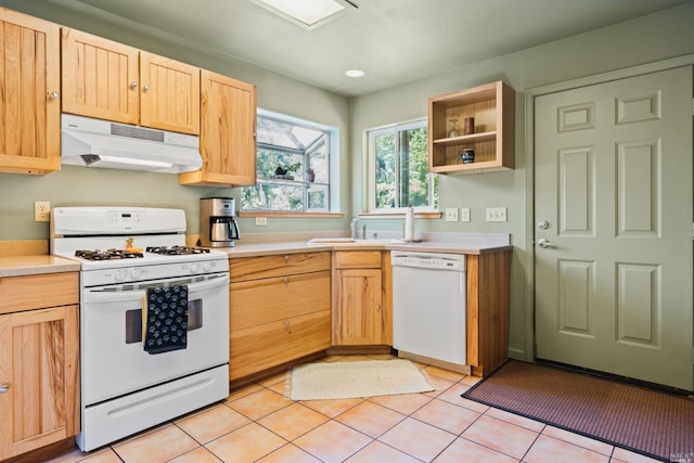 kitchen featuring light tile floors, light brown cabinetry, white appliances, and sink