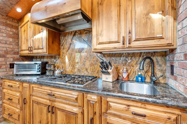 kitchen with brick wall, wall chimney exhaust hood, tasteful backsplash, and sink