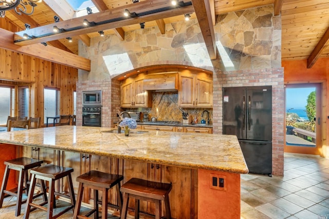 kitchen featuring beam ceiling, sink, light stone counters, and black appliances