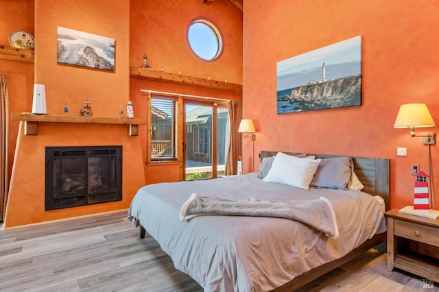 bedroom featuring light hardwood / wood-style floors and a towering ceiling