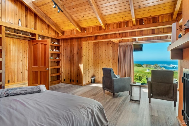 bedroom with light hardwood / wood-style floors, a water view, wood walls, rail lighting, and wooden ceiling