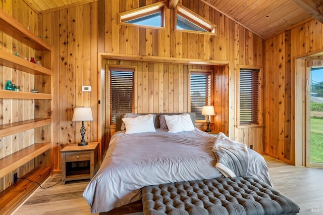 bedroom with light hardwood / wood-style floors, wooden walls, and multiple windows