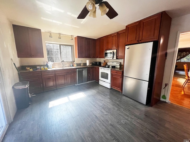 kitchen featuring appliances with stainless steel finishes, dark wood-type flooring, ceiling fan, sink, and rail lighting