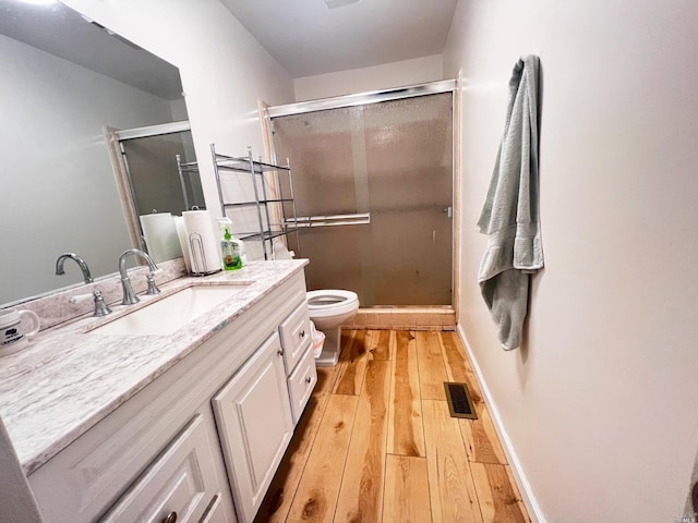 bathroom featuring vanity, toilet, hardwood / wood-style flooring, and an enclosed shower