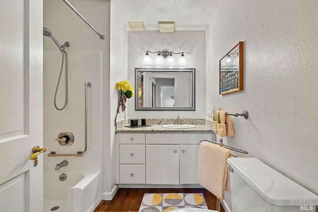 full bathroom featuring toilet, bathtub / shower combination, hardwood / wood-style flooring, a textured ceiling, and vanity