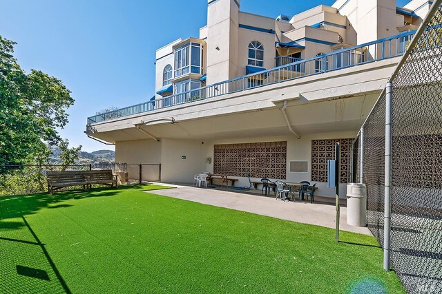 rear view of property with a balcony, a yard, and a patio