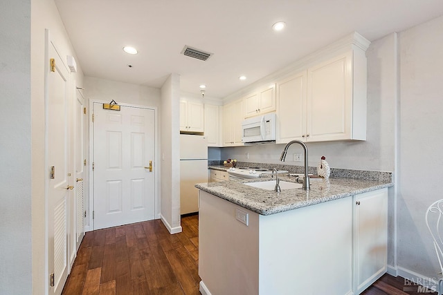 kitchen featuring kitchen peninsula, white appliances, white cabinets, dark wood-type flooring, and light stone countertops