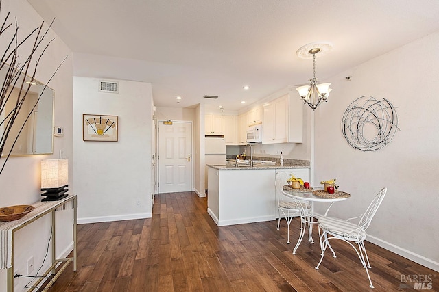 kitchen featuring a chandelier, decorative light fixtures, dark wood-type flooring, white cabinetry, and white appliances