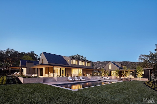 rear view of property featuring outdoor lounge area, a patio, a yard, and an outdoor pool