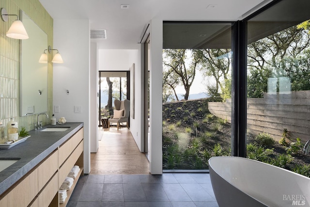 bathroom featuring a sink, a soaking tub, tile patterned flooring, visible vents, and double vanity