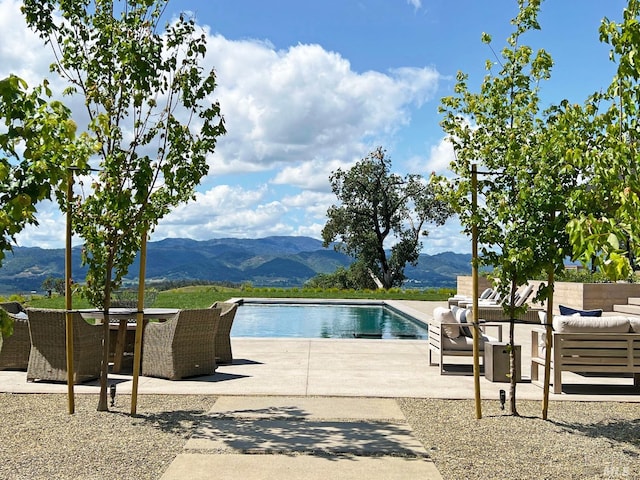 pool with an outdoor hangout area, a patio, and a mountain view