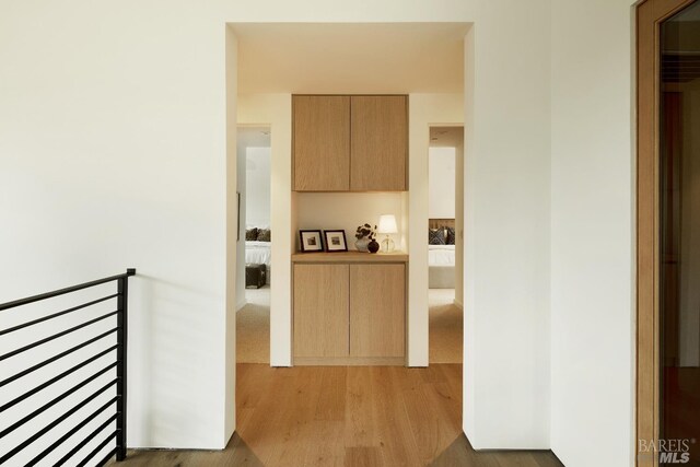 hall featuring an upstairs landing and wood finished floors