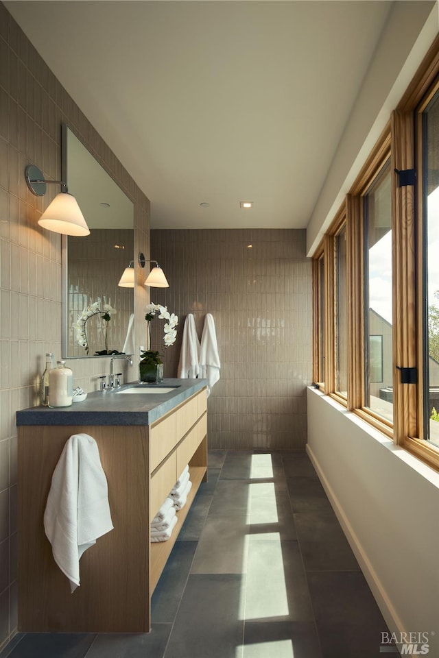 bathroom with tile walls, baseboards, tile patterned flooring, and vanity