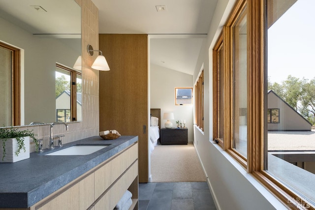 ensuite bathroom with vanity, baseboards, ensuite bath, and vaulted ceiling