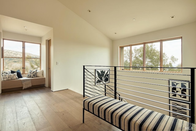 hallway with an upstairs landing, vaulted ceiling, and hardwood / wood-style flooring