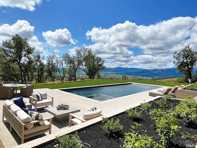 outdoor pool with outdoor lounge area, a patio area, and a mountain view