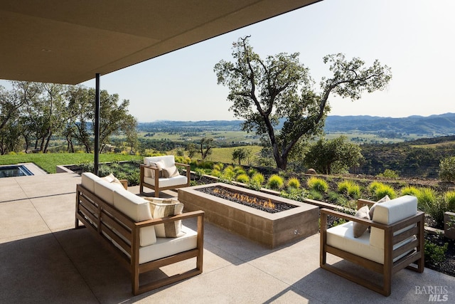 view of patio with a mountain view and an outdoor living space with a fire pit