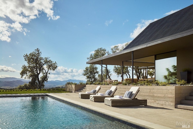 outdoor pool with a mountain view and a patio area