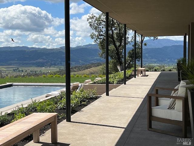 view of patio / terrace with an outdoor pool and a mountain view