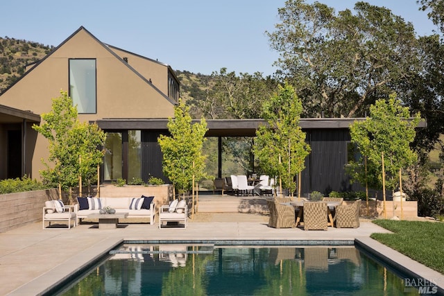 back of property with outdoor lounge area, stucco siding, an outdoor pool, and a patio area