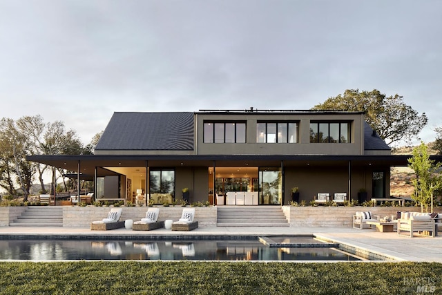 back of property with a patio, stairway, stucco siding, and an outdoor pool