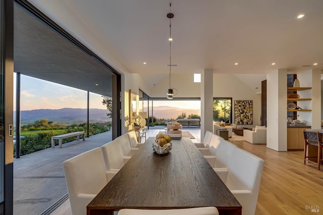 dining room with a mountain view, recessed lighting, vaulted ceiling, and light wood-style floors