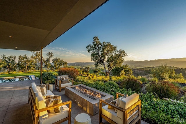 view of patio featuring a mountain view and an outdoor living space with a fire pit