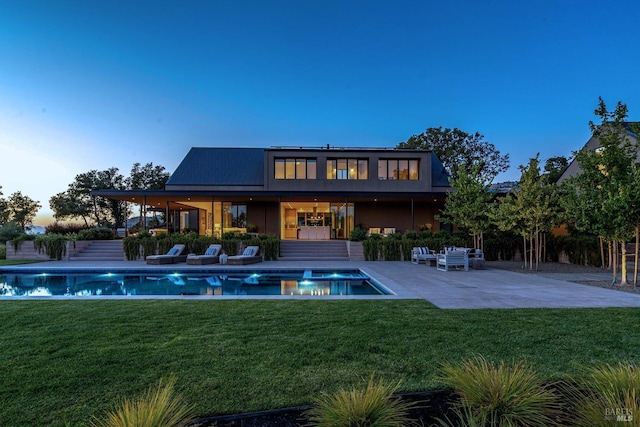 back of house with a patio, a lawn, stucco siding, and an outdoor pool