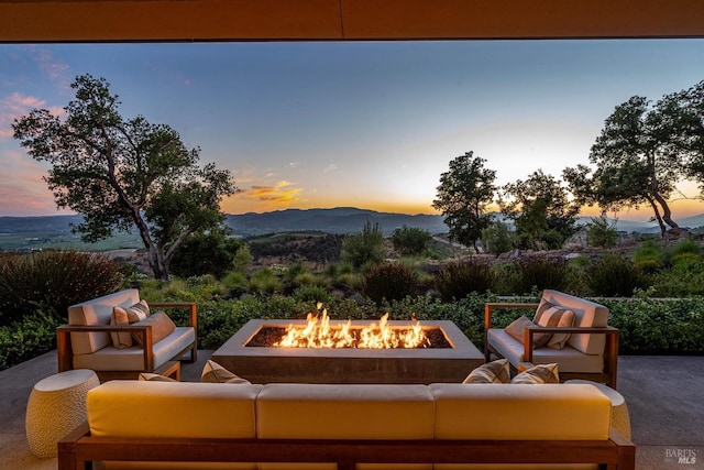 patio terrace at dusk featuring a mountain view and an outdoor living space with a fire pit