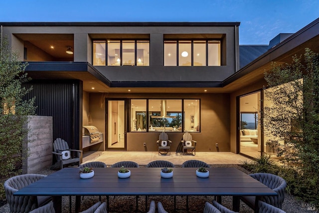 rear view of property with outdoor dining area, stucco siding, and a patio area
