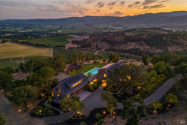aerial view at dusk with a mountain view and a rural view